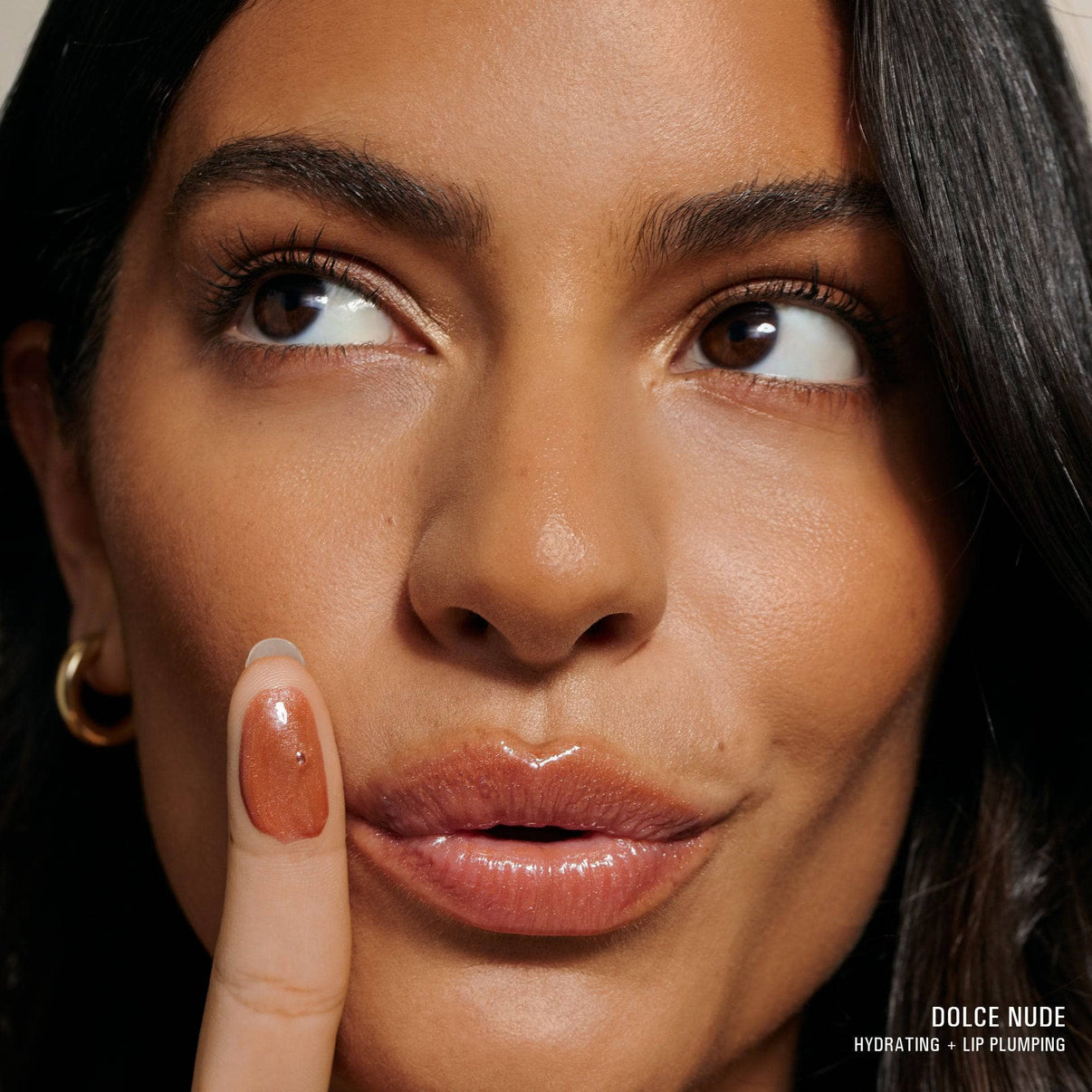 Young woman wearing Hydra-Peptide Lip Butter in shade Dolce Nude with texture swatch on her finger