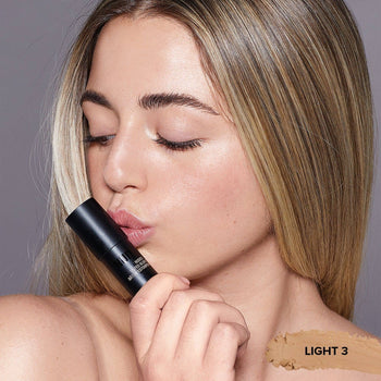 Young woman kissing a Tinted Blur Foundation Stick in shade Light 3