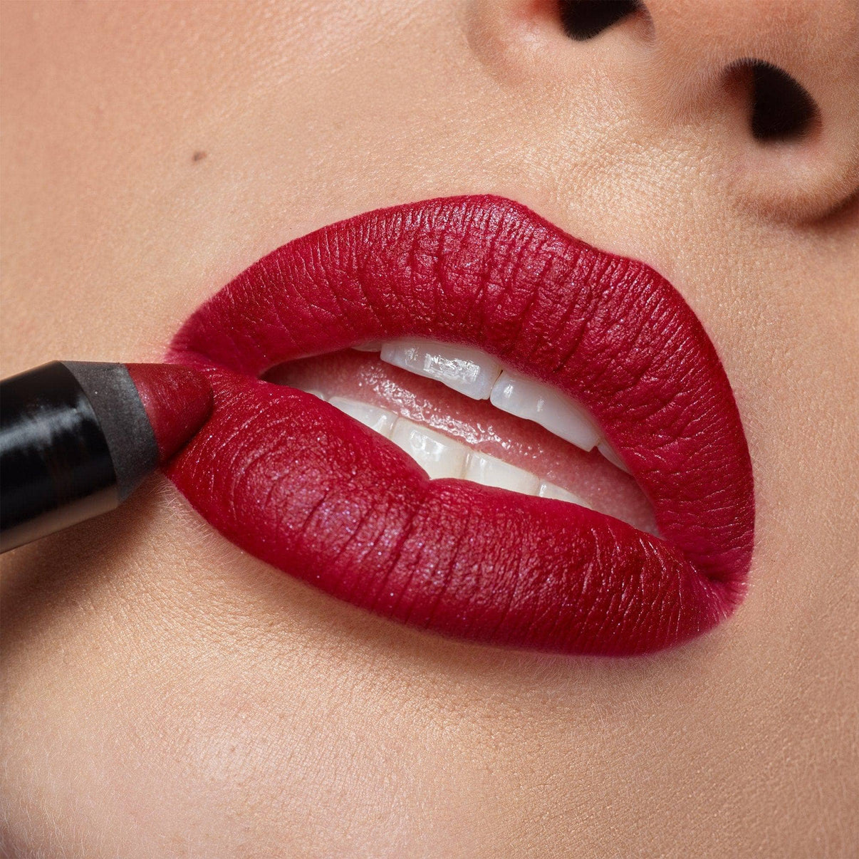 Young woman applying Intense Matte Lip + Cheek pencil in shade raven on her lips